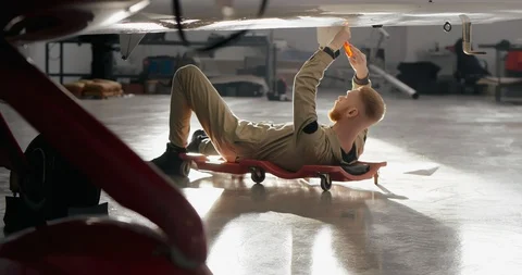 Portrait of aviation maintenance worker lying under aircraft wing Stock Footage 104663318