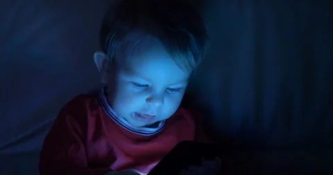Portrait of baby child look at mobile phone tin dark night, too early technology Video stock 130371353
