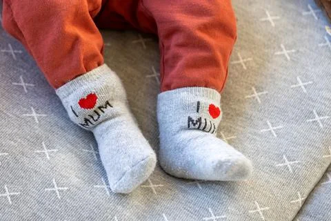 A portrait of a baby's feet with gray socks with, I love mum, written on them Stock Photos
