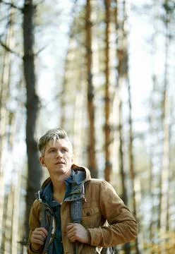 Portrait backpacker man standing in forest, optimistic looking forward, sunny Stock Photos