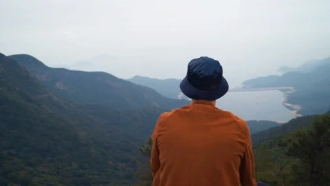 Portrait of bald man sitting on top of the mountain watching the horizon Stock Footage 85580604