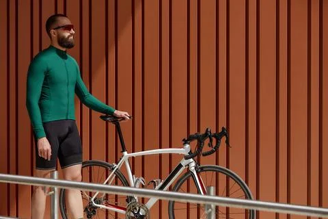 Portrait of bearded guy with bicycle posing over orange wall background. Stock Photos