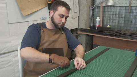 Portrait of bearded leather worker making belts in studio. Stock Footage 94758064