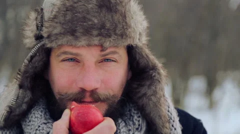 Portrait of a bearded man with an apple in the winter. Stock Footage 59599255