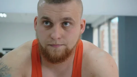 Portrait bearded man training on static bike in gym. Slow motion face fitness Stock Footage 120890933