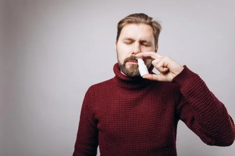 Portrait of bearded man using nasal spray in studio Stock Photos