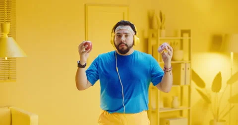 Portrait of bearded young man makes a choice between donut and apple, wearing Stock Footage 165869665