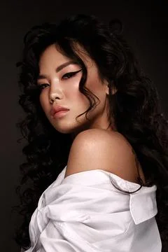Portrait of a beautiful asian woman in a white shirt, with makeup and curls Stock Photos