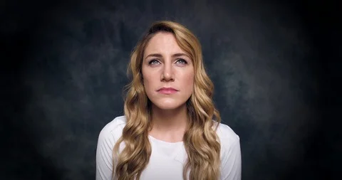 Portrait of a beautiful blonde dramatically closing her eyes on a dark Stock Footage 115106919