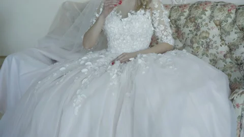 Portrait of beautiful bride sits on sofa, smiles and looks at camera. 4K Stock Footage 86830057