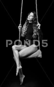 Portrait of beautiful caucasian model posing on rope swing in body dress on b Stock Photos