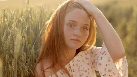 Portrait of a beautiful cute red-haired girl with freckles standing in the field Video stock 235031763