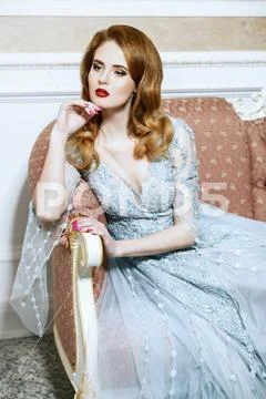 A portrait of a beautiful elegant woman in the wedding dress on the couch. Fa Stock Photos
