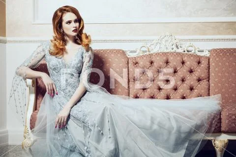 A portrait of a beautiful elegant woman in the wedding dress on the couch. Fa Stock Photos