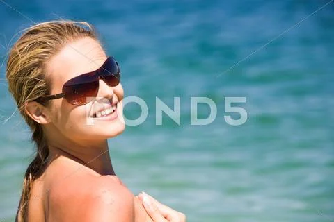 Portrait of beautiful female in sunglasses on background of blue ocean Stock Photos