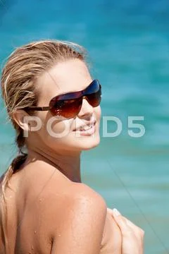 Portrait of beautiful female in sunglasses on background of blue ocean Stock Photos