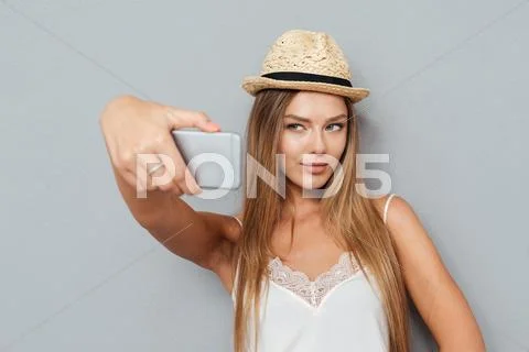 Portrait of beautiful girl in hat making selfie with smartphone Stock Photos