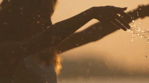 Portrait of beautiful girl splashing in the river against bright sunset Stock Footage