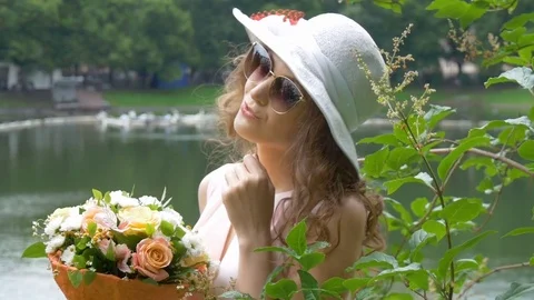 Portrait of a beautiful girl in sunglasses and a white hat with flowers. Stock Footage