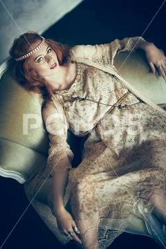 Portrait of a beautiful red-haired young woman sitting in vintage armchair. H Stock Photos