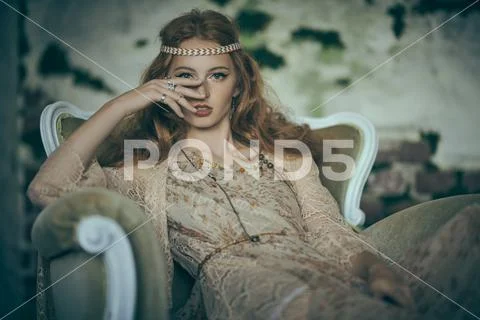 Portrait of a beautiful red-haired young woman sitting in vintage armchair. H Stock Photos
