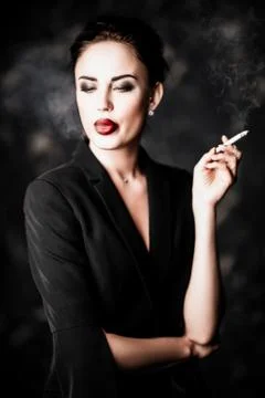 A portrait of a beautiful sexy woman wearing a black blazer and smoking a cig Stock Photos