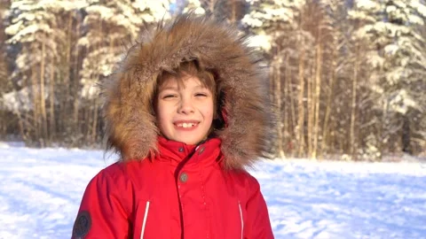 Portrait of a beautiful smiling boy in a red jacket with a hood against the Stock Footage 168105454