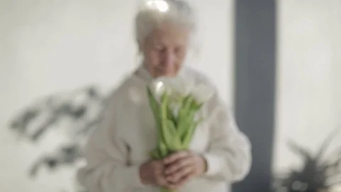 Portrait of a beautiful smiling elderly senior woman with flowers Stock Footage 85435522