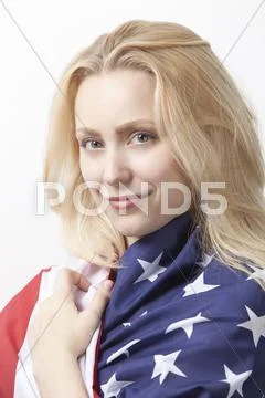 Portrait of beautiful young Caucasian woman wrapped in American flag against Stock-Fotos