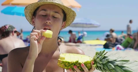 Portrait of a beautiful young girl at the sea, holding a pineapple in a swimsuit Stock Footage