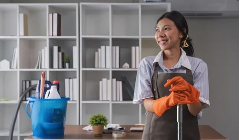 Portrait of a beautiful young housewife smiling and happy, holding cleaning Stock Photos