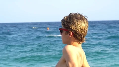 Portrait of beautiful young man looking out over the sea on Brighton beach. Stock Footage 79896762