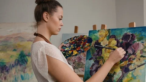 Portrait of beautiful young painter holding paintbrush and color palette while Stock Footage 74207572