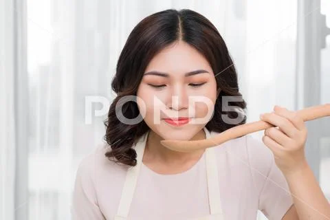 Portrait of beautiful young woman cooking soup with vegetables at home. Stock Photos