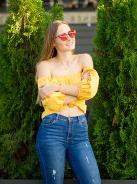 .Portrait of a beautiful young woman in jeans, a yellow blouse and red sungla Stock Photos