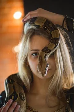 Portrait of beautiful young woman with a python on face Photos