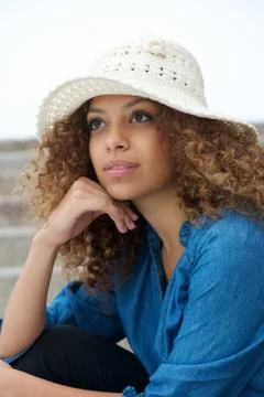 Portrait of a beautiful young woman sitting outdoors with hat Foto stock