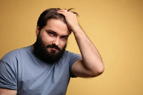 Portrait of big man with beard, posing over yellow background. Isolated. Fotos Stock