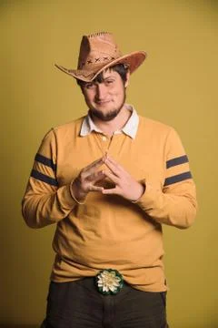 Portrait of big man in a cowboy hat and a yellow shirt. Young man. The studio Stock Photos
