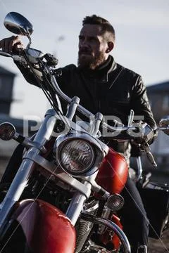 Portrait of biker sitting on motorcycle and looking away Stock Photos