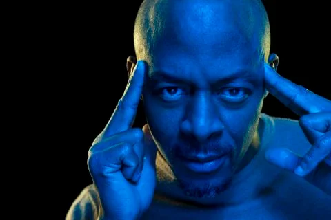 Portrait of a black man with concentration expression. Vibrant blue light Stock Photos