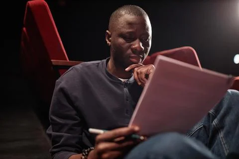 Portrait of Black Man Reading Script in Theater And Rehearsing For Performance Foto stock