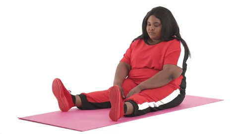 Portrait of black plus size model doing pilates mat saw exercise isolated on Video stock 134574557