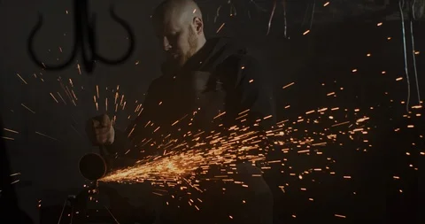 Portrait of a blacksmith perfecting his blade in a dark interior of his metal Stock Footage 122198355