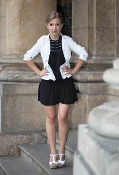 Portrait of a blond girl wearing a white jacket and black dress with white pl Stock Photos