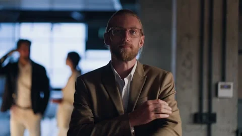 Portrait of a blond man with a beard who adjusts his light brown suit, folds his Stock Footage 250602553