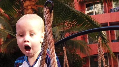 Portrait of a blond two-year-old boy who is sitting on the bridge Stock Footage 106287014
