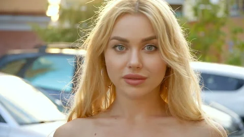 Portrait of a blonde with full lips and blue eyes on a background of parking Vídeo Stock 114624995