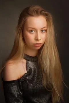 Portrait of a blonde in the Studio on a dark background in a black shiny blou 스톡 사진