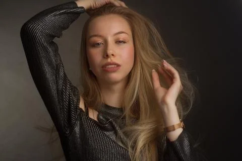Portrait of a blonde in the Studio on a dark background in a black shiny blou Stock Photos